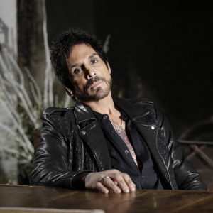 A photo of Deen Castronovo sitting at a table looking into the camera.